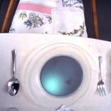 video installation of stop-motion projected onto dinner plate from below at dinner table setting, upholstered chairs