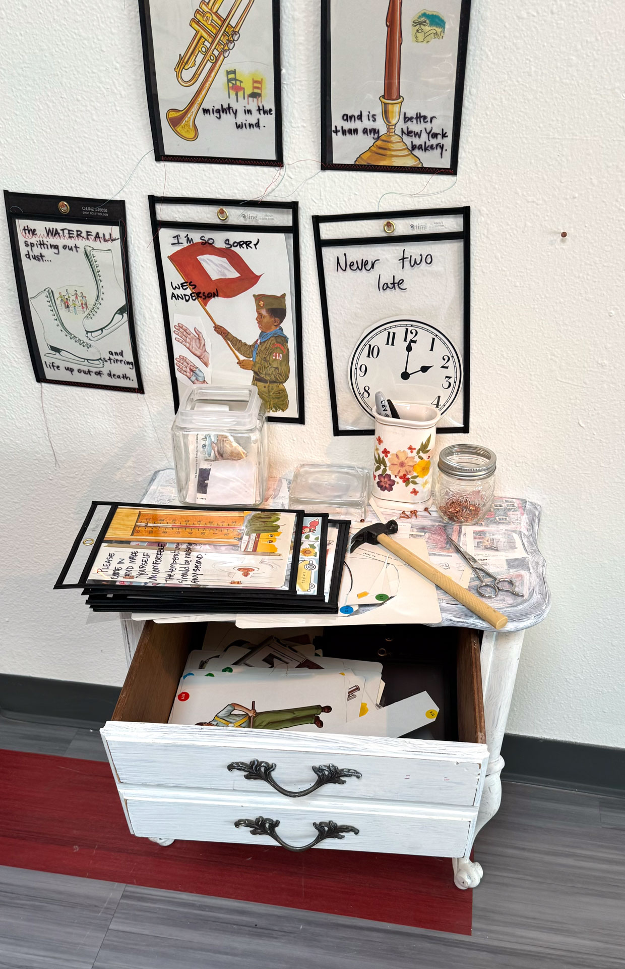 installation with wood table cut in half against wall, job folder, collage materials, audience participation