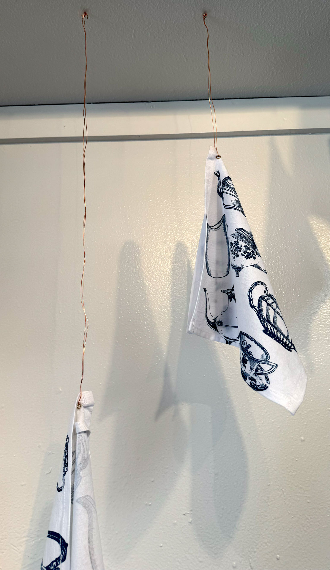 installation with silkscreen napkins attached to ceiling in an arch travelling from a box to a pitcher