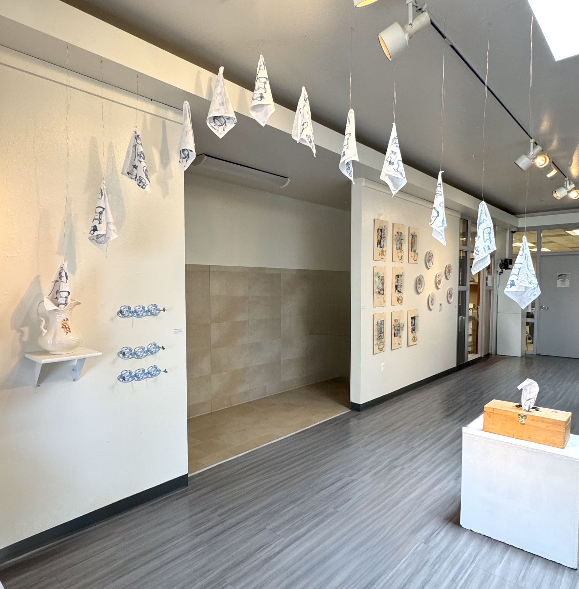 installation with silkscreen napkins attached to ceiling in an arch travelling from a box to a pitcher
