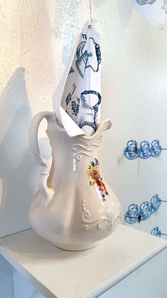 installation with silkscreen napkins attached to ceiling in an arch travelling from a box to a pitcher