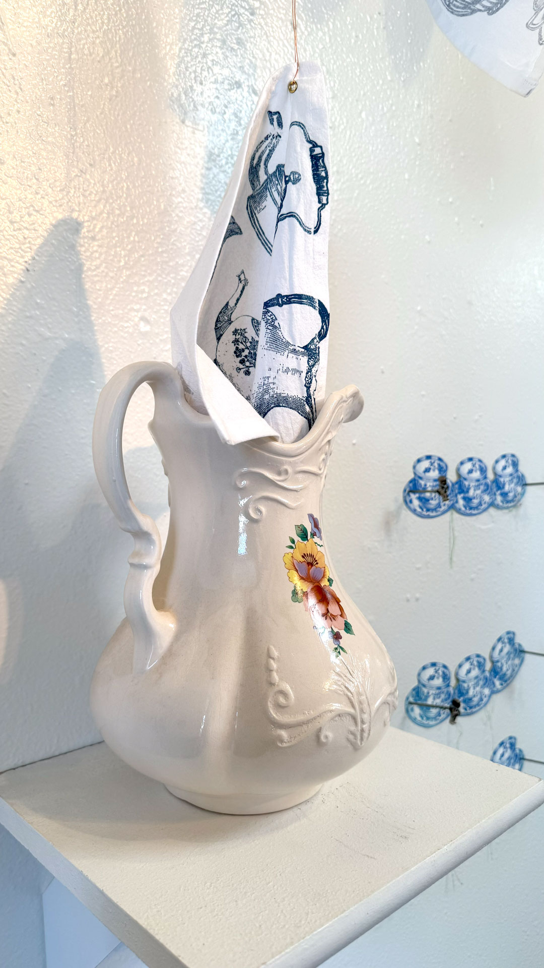 installation with silkscreen napkins attached to ceiling in an arch travelling from a box to a pitcher
