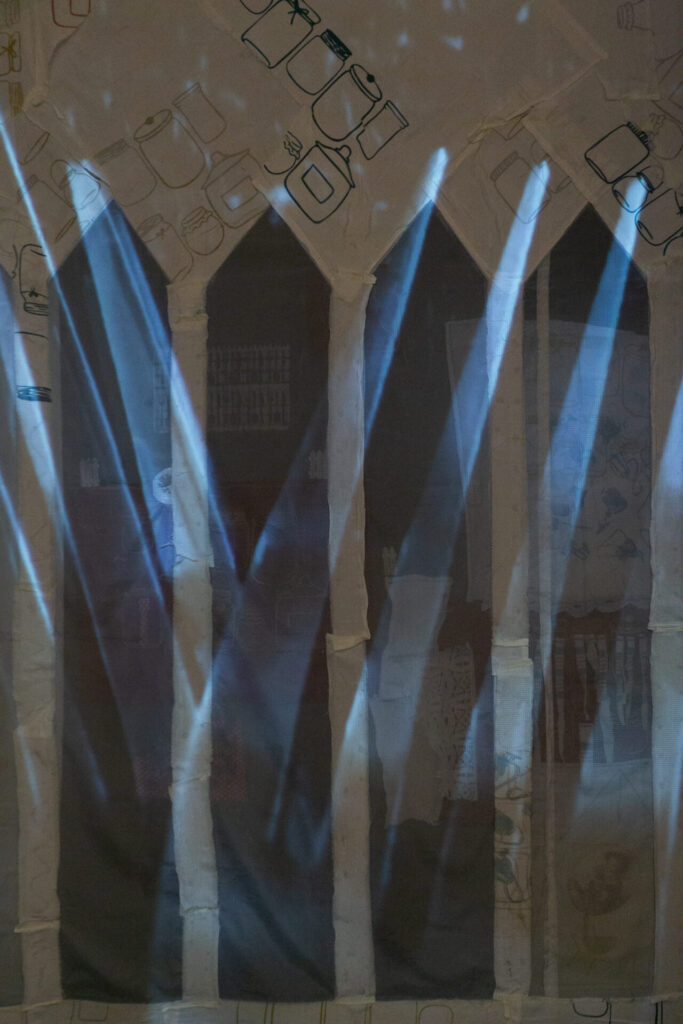 video installation of floating/falling cutlery on silcreened white fabric with sheer fence, fabric collage